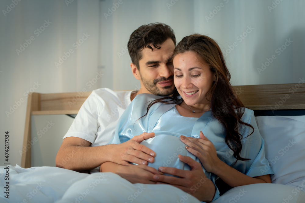 Pregnant woman with husband in bedroom with the atmosphere of having fun talking Pregnant woman with husband in bedroom with the atmosphere of having fun talking