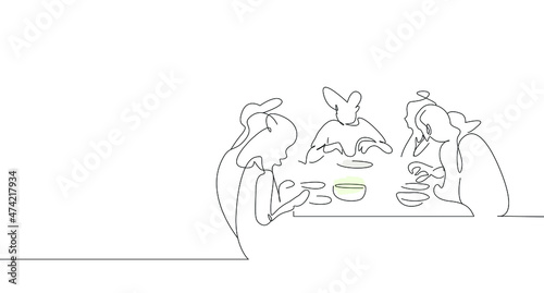 They are happily eating together at a large family dinner table.