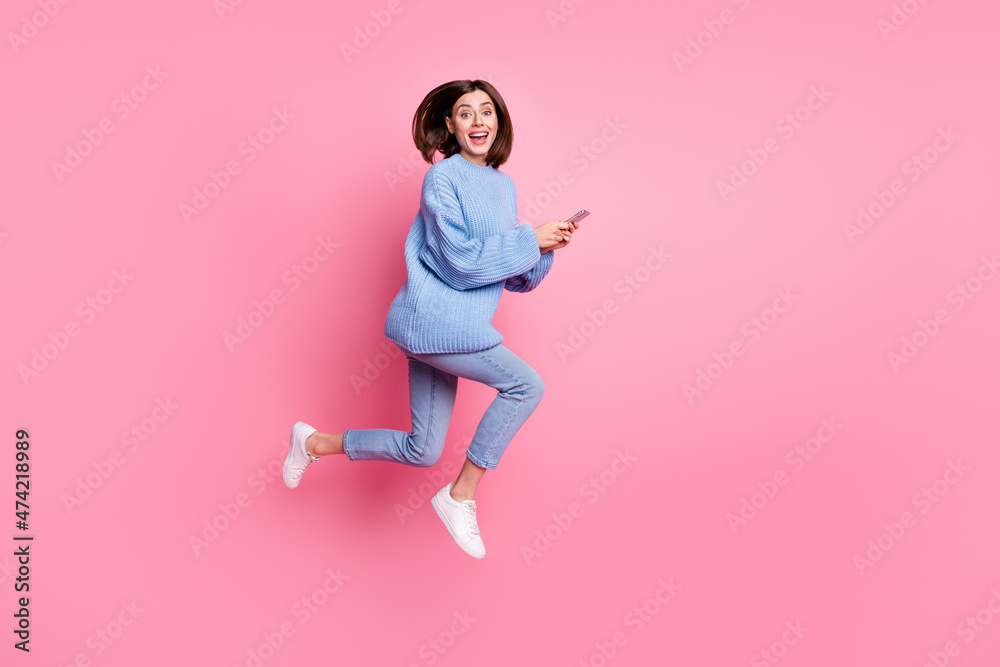 Full length body size view of attractive cheery trendy girl jumping using gadget having fun smm isolated over pink pastel color background
