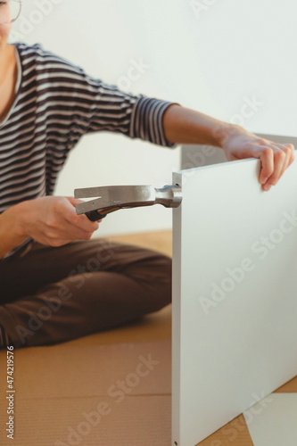Close-up of a woman's hands driving a nail with a hammer.
