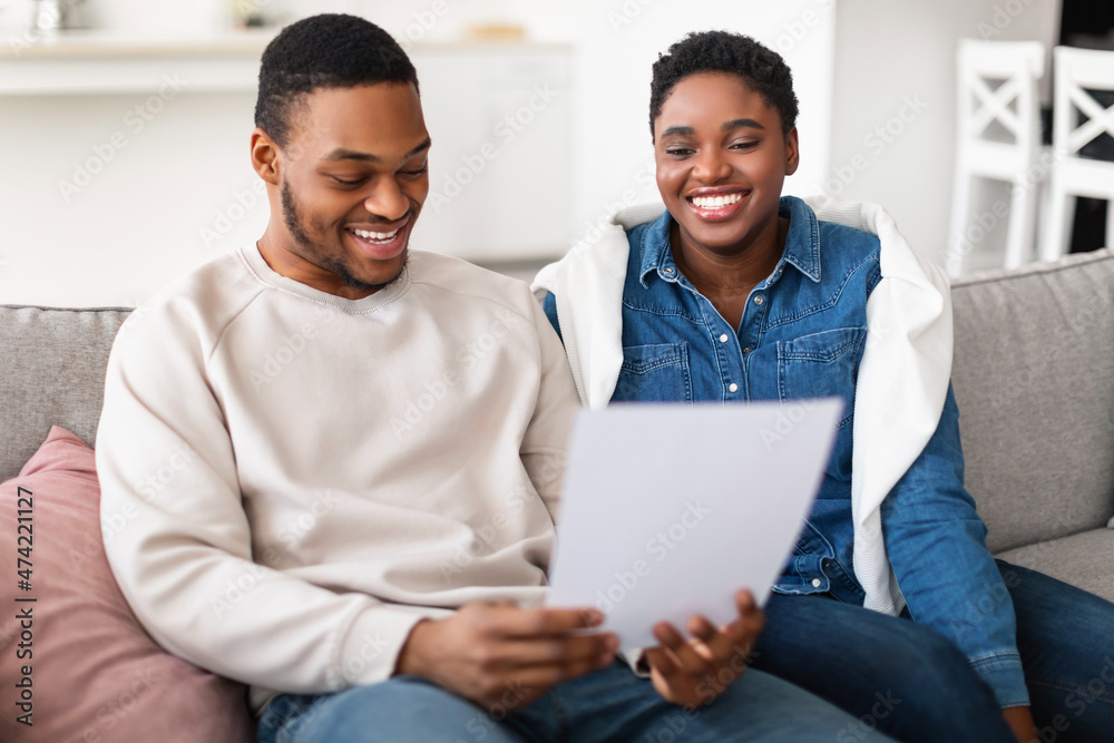 Smiling afro couple reading documentation at home