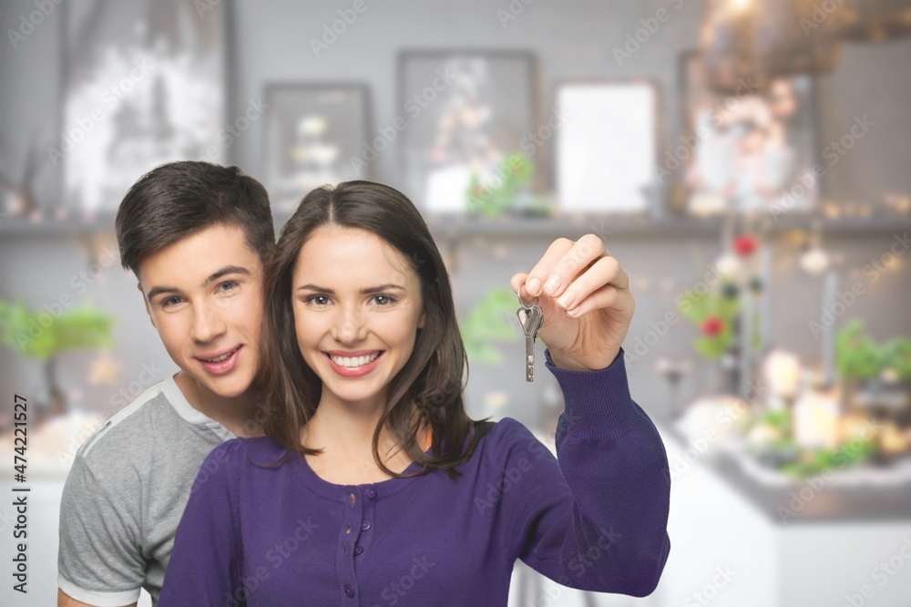 Cheerful lady with boyfriend, showing house key indoors. Lovely couple posing in new apartment Cheerful lady with boyfriend, showing house key indoors. Lovely couple posing in new apartment