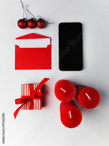 On a white background red Christmas candles, gift, envelope, smartphone screen. Background for postcards