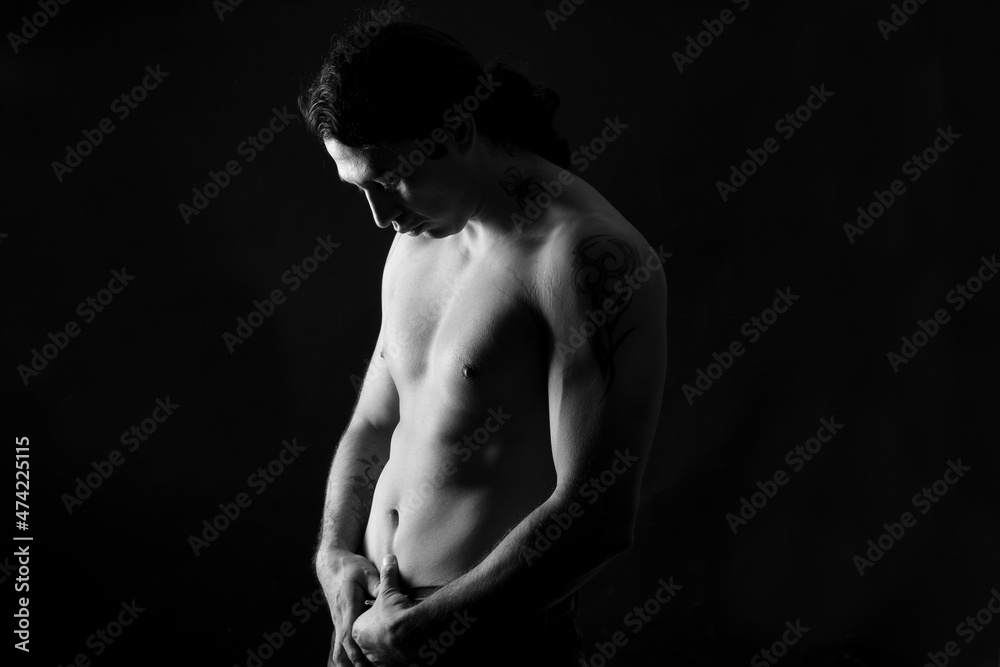 black and white low key portrait of shirtless man looking at down black background black and white low key portrait of shirtless man looking at down black background