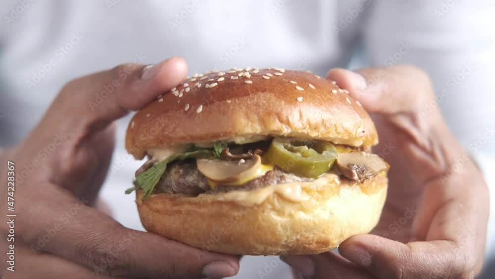 hand holding beef burger on table close up hand holding beef burger on table close up