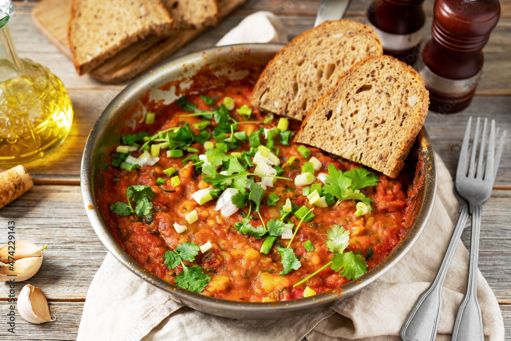 Homemade vegetarian stew with beans, vegetables and cilantro in a frying pan on a gray wooden culinary background close-up Homemade vegetarian stew with beans, vegetables and cilantro in a frying pan on a gray wooden culinary background close-up
