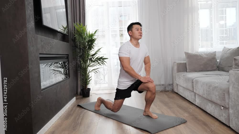 Strong asian guy is exercising at home doing sports exercises The athlete stretching the legs stimulating the work of all muscles of the body. Men, house and sports lifestyle. Strong asian guy is exercising at home doing sports exercises The athlete stretching the legs stimulating the work of all muscles of the body. Men, house and sports lifestyle.