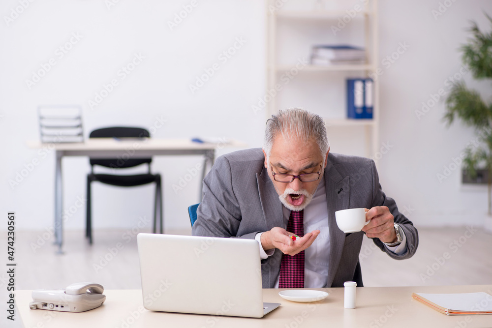 Old businessman feeling bad at workplace Old businessman feeling bad at workplace