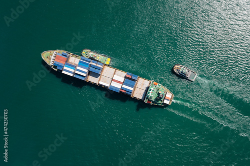 container ship and tugboat dragging floating in green sea, business and industry Transportation cargo logistics services of international by container ship in ocean