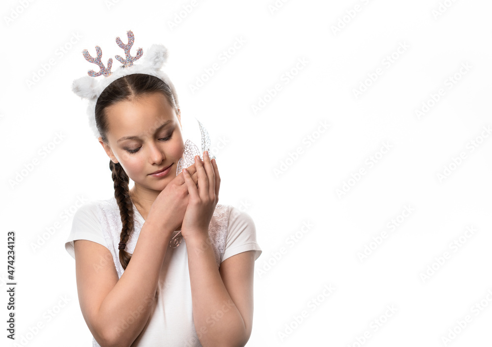 Portrait of smiling girl in Christmas deer headband holding silver Christmas decoration twig against white background Portrait of smiling girl in Christmas deer headband holding silver Christmas decoration twig against white background
