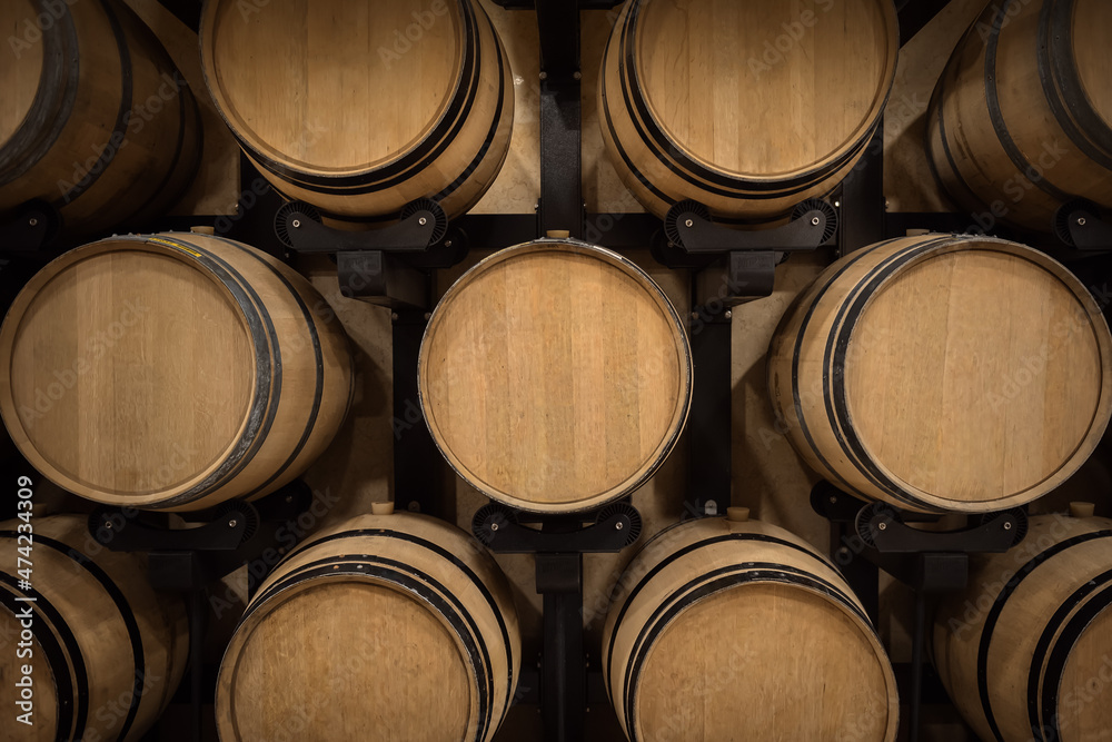 Stacked wooden wine barrels in winery vault, winemaking pattern
