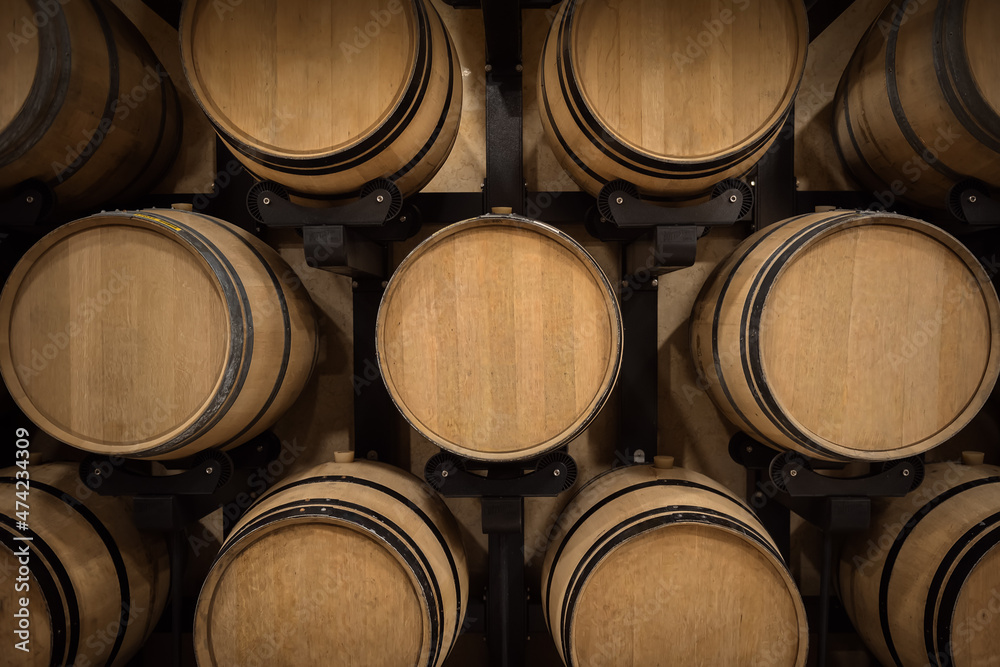 Stacked wooden wine barrels in winery vault, winemaking pattern Stacked wooden wine barrels in winery vault, winemaking pattern