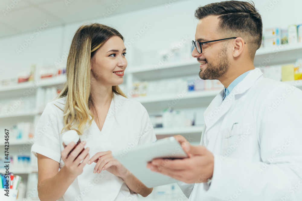 Happy young male and female colleagues pharmacist working in a pharmacy Happy young male and female colleagues pharmacist working in a pharmacy