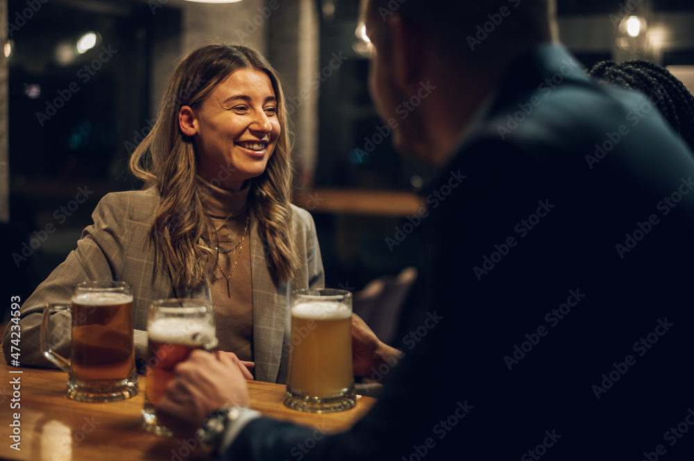 Cheerful colleagues drinking beer in the bar together after work and using a tablet Cheerful colleagues drinking beer in the bar together after work and using a tablet