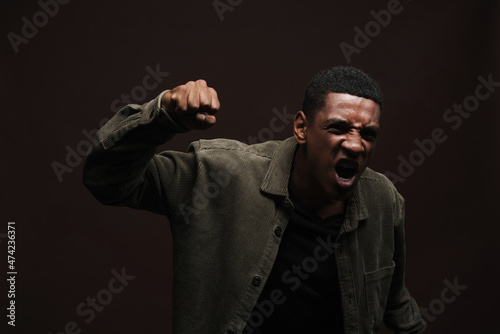 Young black man screaming while making winner gesture