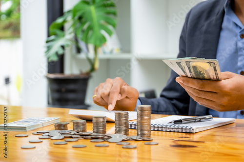business man holding banknotes and calculating money, man saving money for household expenses Monthly utility bills, family budget calculations, investment or personal savings strategies.