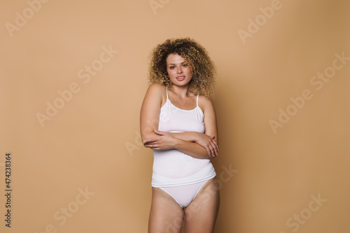 Young curly woman dressed in underwear looking at camera