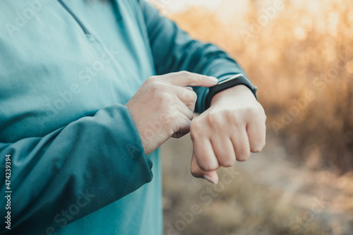 Active sport woman setting up the fitness smart watch for timing running workout.