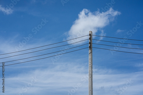 Power lines pass on high-voltage poles against a bright sky background.