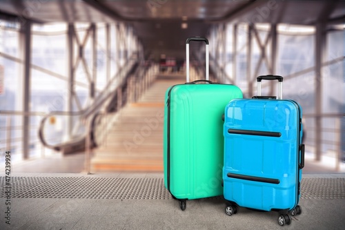 Modern stylish suitcases standing in empty airport hall, unrecognizable traveller's luggage