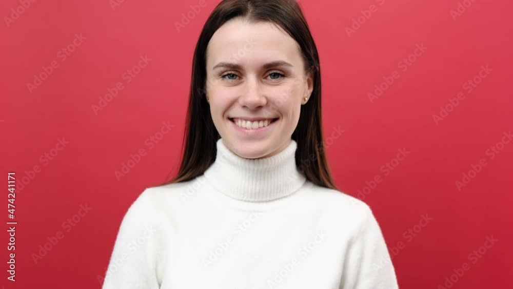 Portrait of beautiful young caucasian woman winking to camera, flirting expression, blinking eye as having cunning idea, wears knitted sweater, posing isolated over red color background wall in studio Portrait of beautiful young caucasian woman winking to camera, flirting expression, blinking eye as having cunning idea, wears knitted sweater, posing isolated over red color background wall in studio