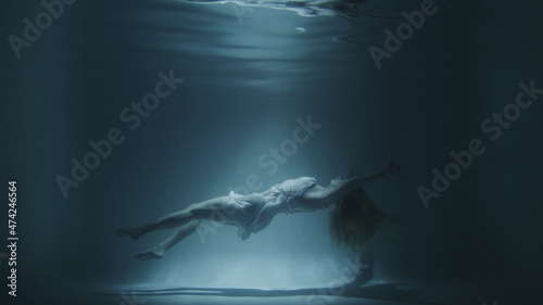 girl in a white dress swims underwater photo