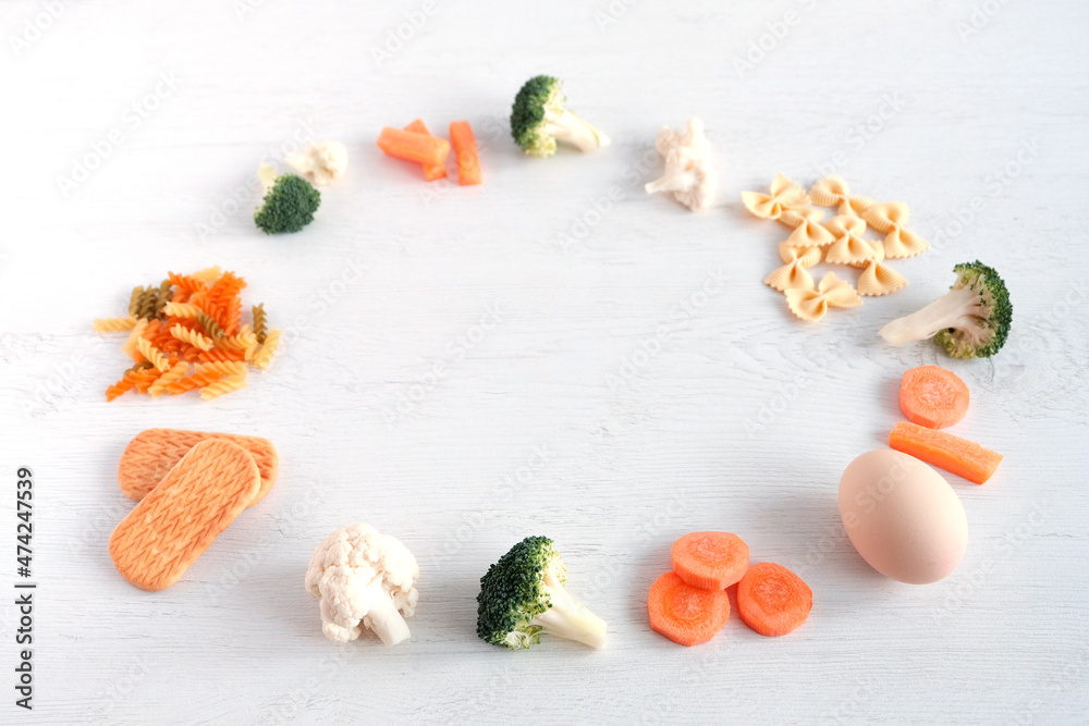 Complementary feeding of a child at an early age. Vegetables: carrots, cauliflower, broccoli: cereals, biscuits, eggs on a light wooden background. Correct baby food