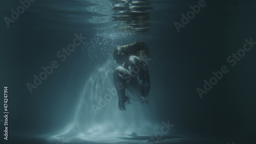 underwater gymnastics of a beautiful girl in a white dress