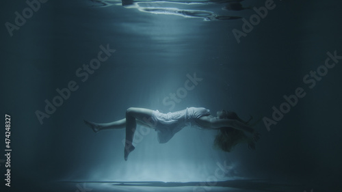 girl in a white dress swims underwater