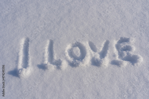 Text I love on a white fresh snow in winter, close up
