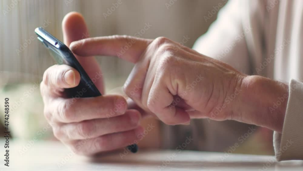 Elderly people are active users of gadgets and the Internet theme. Close up of hand of an elderly man using smartphone clicking on screen while browsing content. Selective focus Elderly people are active users of gadgets and the Internet theme. Close up of hand of an elderly man using smartphone clicking on screen while browsing content. Selective focus