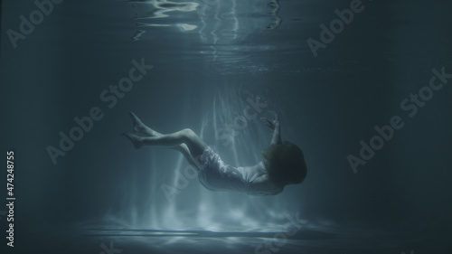 a girl in a white dress falls under the water