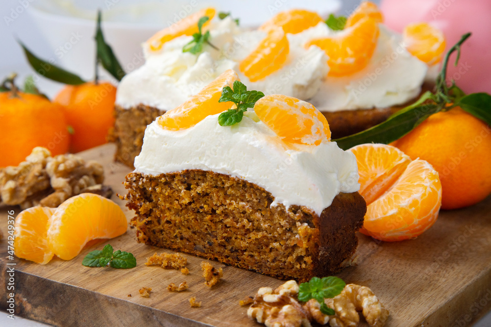 Vegan tangerine sponge cake with a giant frosting and mandarin orange wedges on a wooden board. Vegan tangerine sponge cake with a giant frosting and mandarin orange wedges on a wooden board.