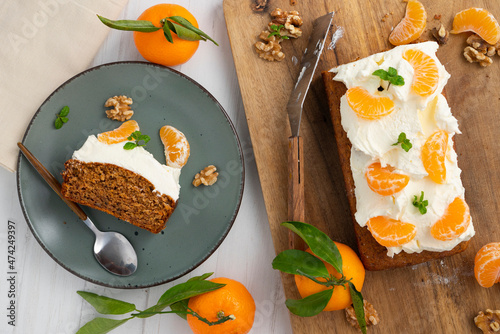 Quadro em tela Vegan tangerine sponge cake with a giant frosting and mandarin orange wedges on a wooden board