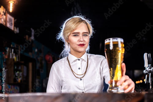 Girl bartender creates a cocktail behind the bar photo