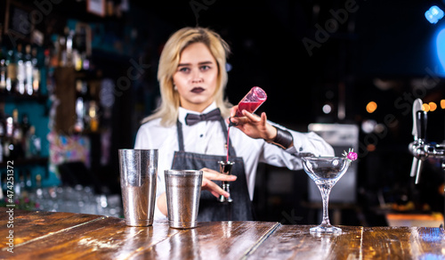 Girl bartender creates a cocktail in the saloon photo