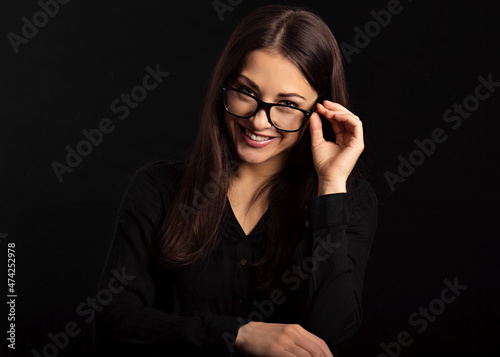 Beautiful thinking happy business woman  looking happy in eye glasses and holding spectacles in casual black t-shirt on black background with empty copy space. Closeup