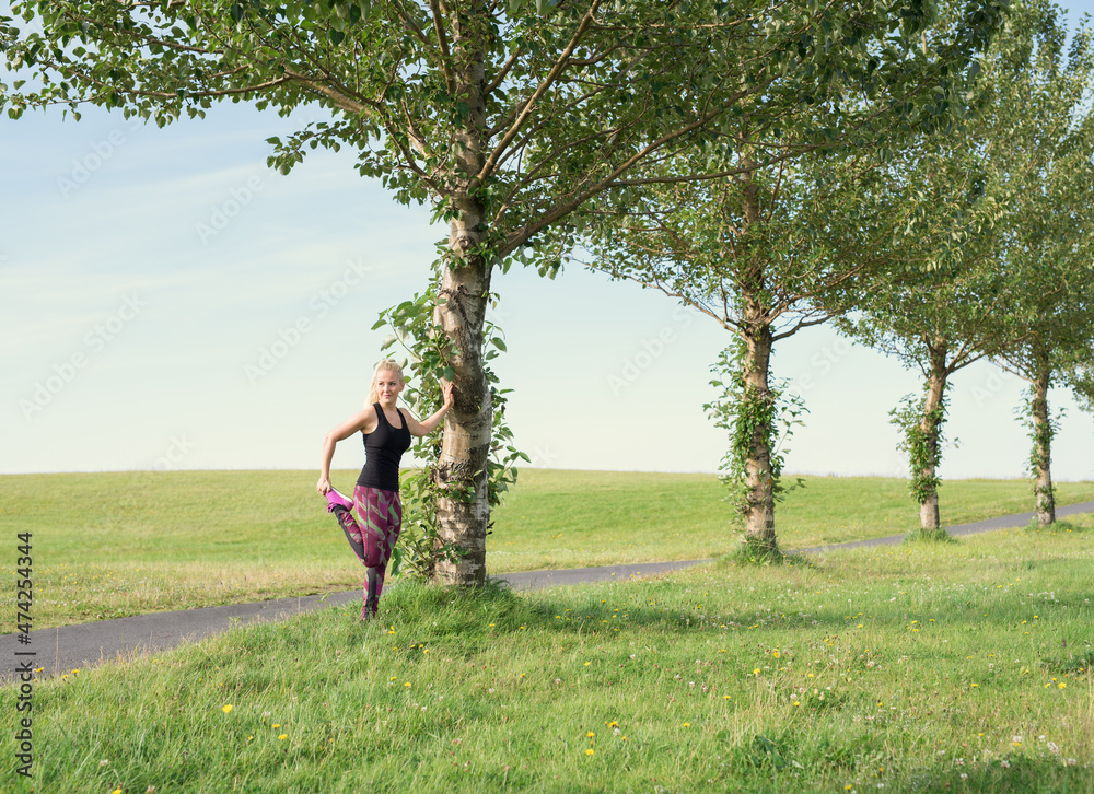 Fit woman warming up near tree before running in nature Fit woman warming up near tree before running in nature
