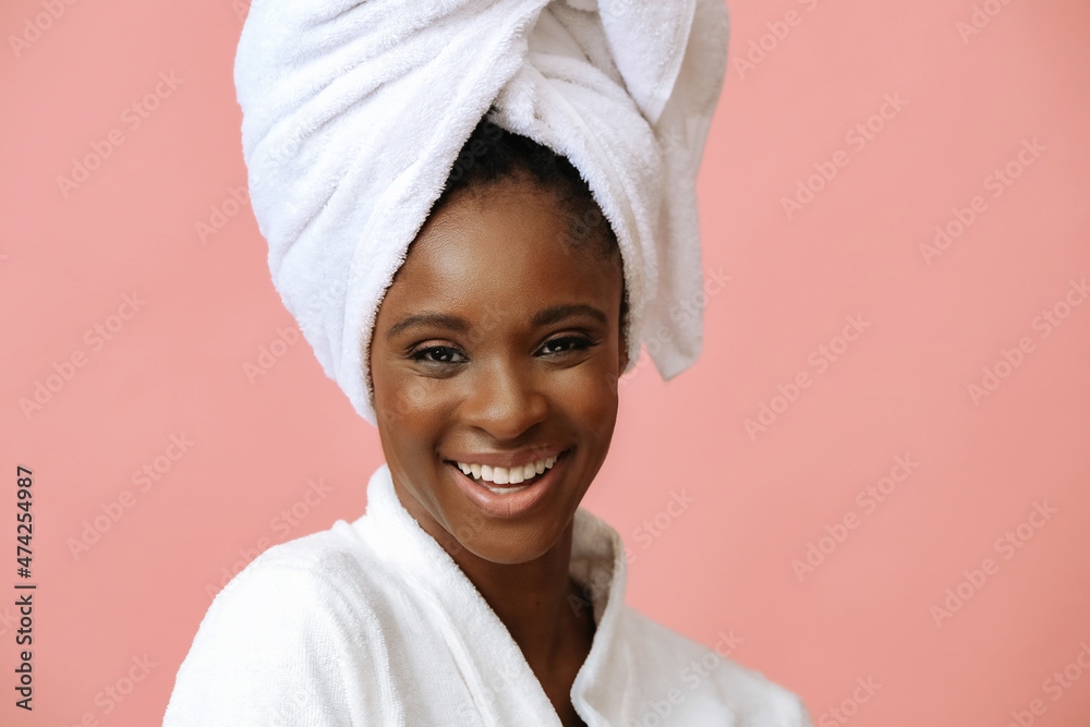 Young beautiful woman in bathrobe with white towel on head posing on pink background - obrazy, fototapety, plakaty 