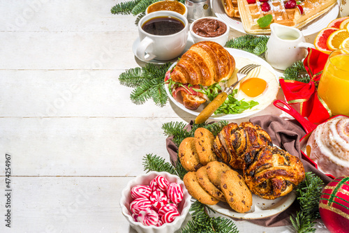Festive Christmas morning breakfast or brunch table, with traditional foods – pancakes, Belgian waffles, fried eggs, croissant, stolen, cookies, with orange juice and coffee, cinnamon rice porridge 