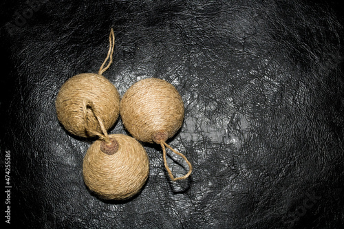 Three rustic Christmas ball ornaments made of jute burlap and acorn caps on black leather background. Minimal concept, handmade decoration for New Year in woody style. photo