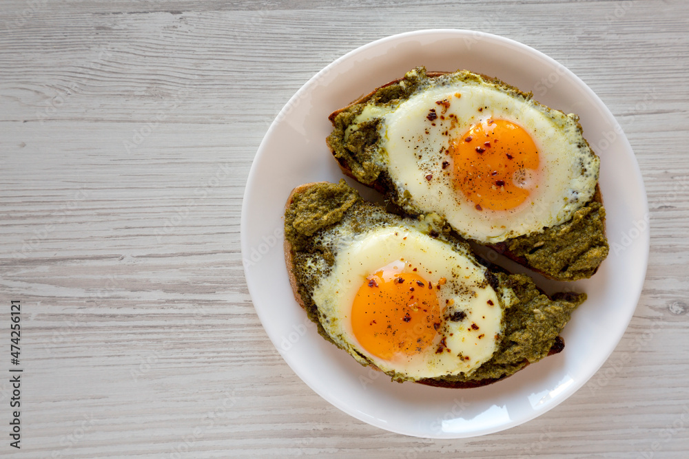 Homemade Pesto Egg Toast on a white plate, top view. Flat lay, overhead, from above. Copy space.