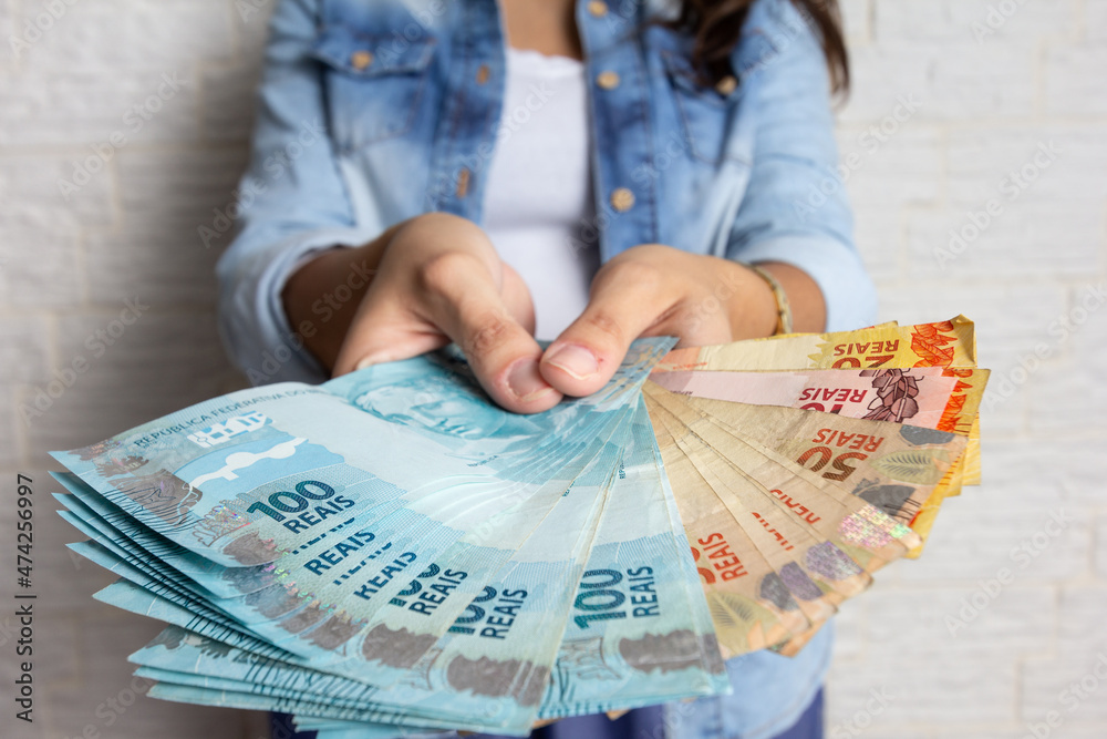 Closeup of woman holds Brazilian currency in hands. Business, income, loan, pay, buy, wealth concept.