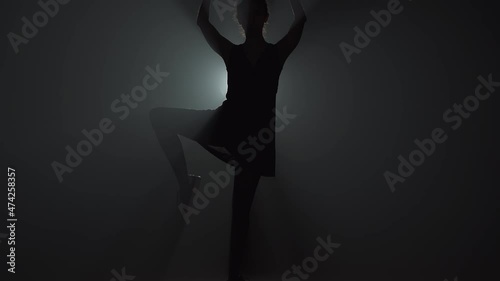 Woman dancer raising leg with backlight