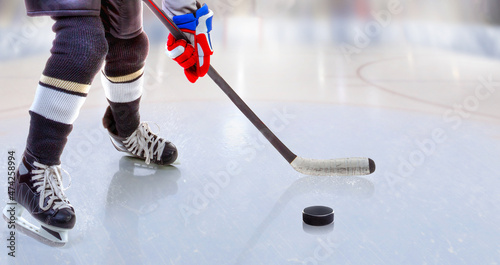 Close up of ice hockey player with stick on ice rink controlling puck