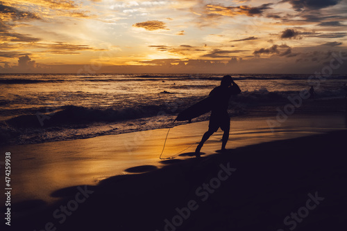 Unrecognizable tourist with surfboard walking on beach