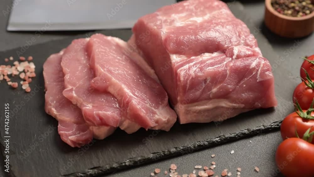 Raw pork steak on a cutting board with herbs and spices