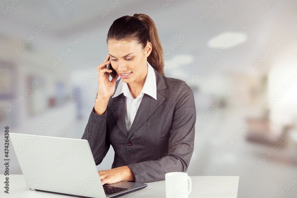 happy young worker with laptop speaking on a smartphone in modern beauty salon. happy young worker with laptop speaking on a smartphone in modern beauty salon.