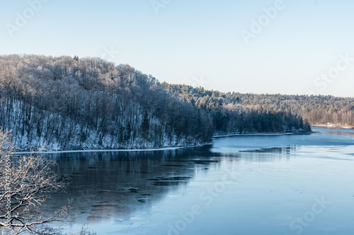 a high angle view to a frozen lake with a forest near it