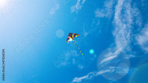 Kite blue sky. Colorful high flying toy. Air kite fly on wind clouds. Rainbow kite in summer background. Concept of dreams  freedom  childhood.